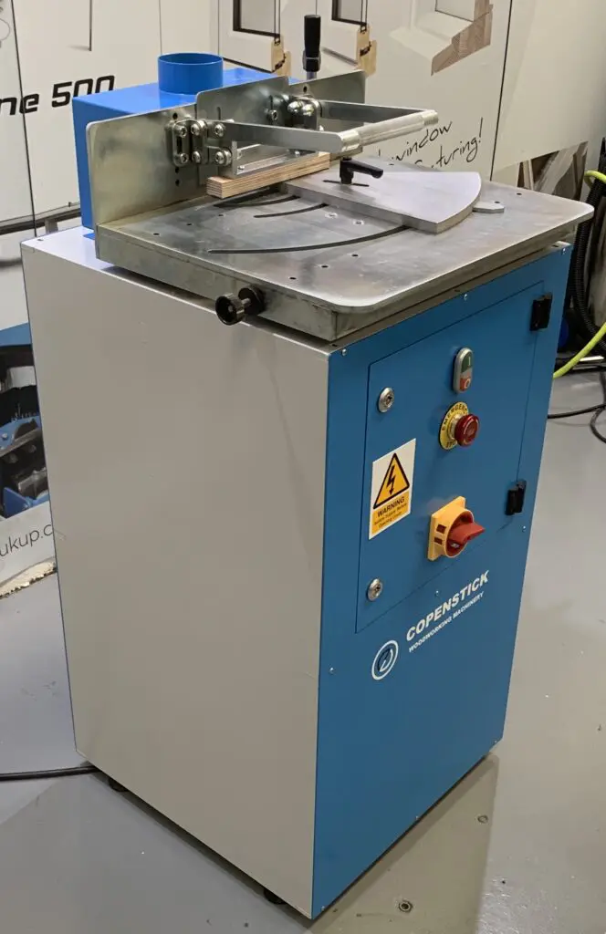 Copenstick end scribe machine with blue and white cabinet, red emergency stop button, and metal work table top
