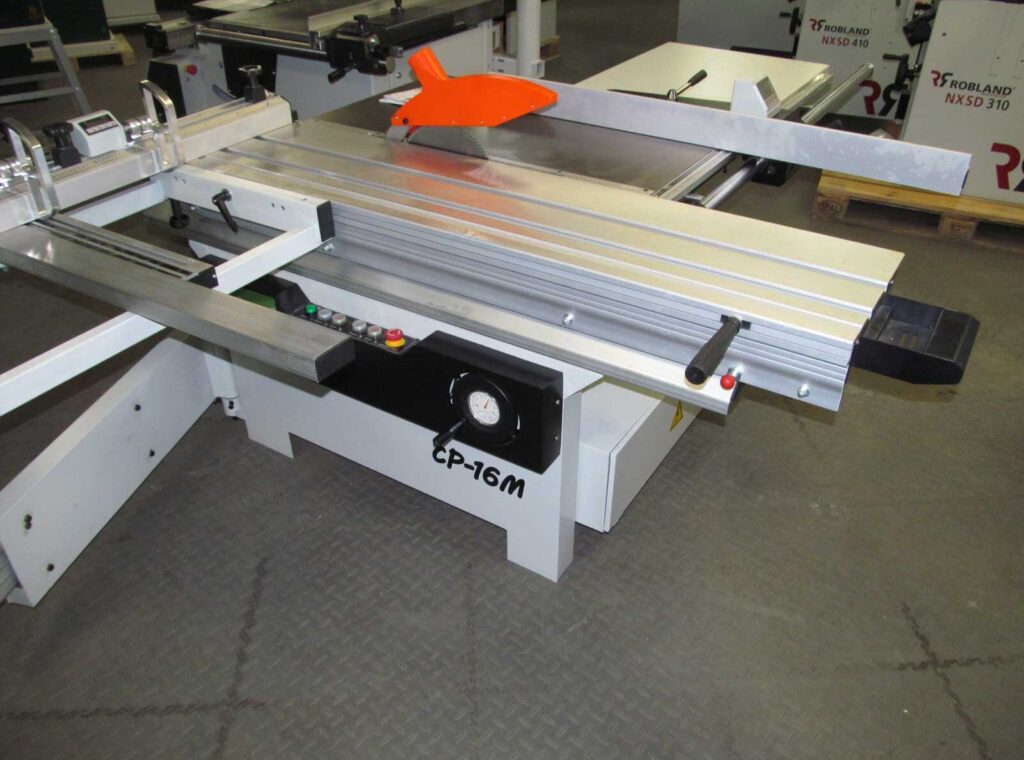 Dominion CP-16M panel saw with sliding table, orange blade guard, and control panel, displayed on a workshop floor.