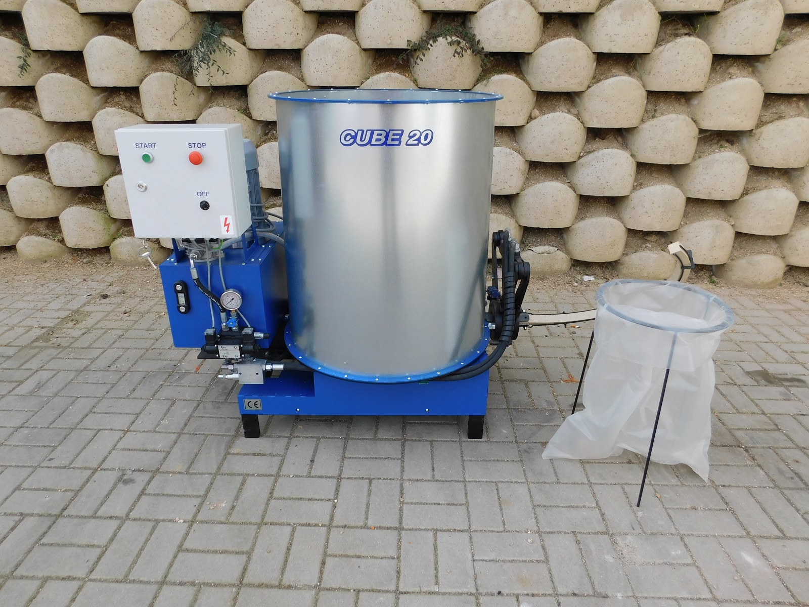 Cube 20 industrial briquette machine on a blue base with a control panel showing start and stop buttons, alongside a filter bag