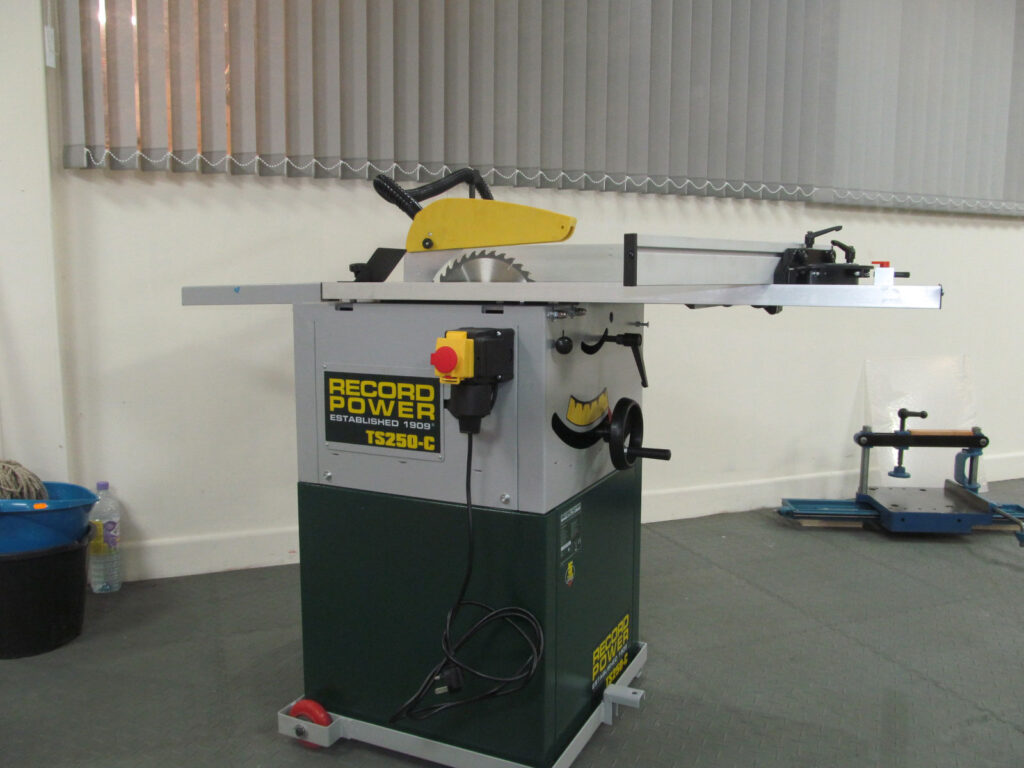 Record Power TS250-C cabinet table saw with rip fence, circular blade guard, and red emergency stop button, in a workshop