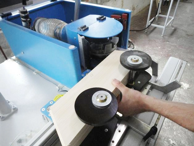 Worker guiding a wooden arch through a Soukup Arcus machining centre with rotating disc rollers